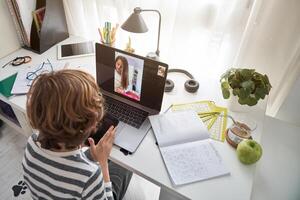 Boy doing homework during call with classmate photo