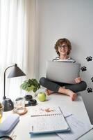 Smiling boy using netbook during online studies at home photo