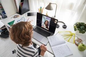 Boy doing homework with classmate during call photo