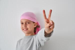 Cute child demonstrating V sign and smiling against white backgr photo