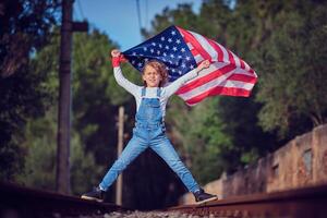 Child with flag of America celebrating Independence Day on railway photo
