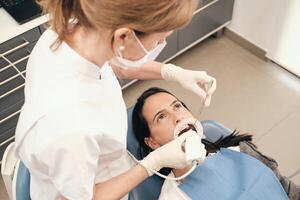 Unrecognizable dentist making teeth scan to woman photo