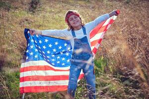 Positive boy having fun with USA flag on meadow photo