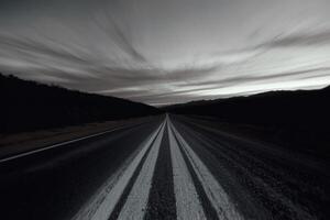 Mysterious road stretches into the distance under a twilight sky in a remote landscape with dark mountains photo