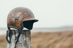 Rusty helmet resting on a weathered post by the coast. photo