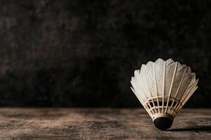 Shuttlecock resting on a rustic wooden surface. photo