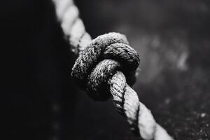 Intricate knot tied in a sturdy rope on a dark background. photo