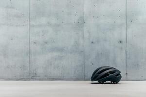 Cycling helmet resting against concrete wall in sleek light. photo
