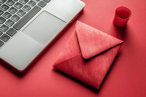 Creative workspace with red envelope and laptop on table. photo
