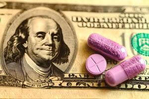 Colorful capsules resting on a hundred dollar bill in close proximity. photo