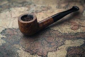 Smoke curling above an antique map with a pipe photo