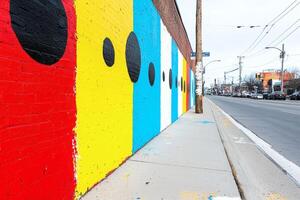 Vibrant street mural brightens urban landscape with colorful patterns and large dots on a cloudy day photo
