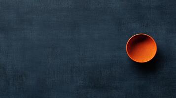 Bright orange bowl resting on a deep blue table, creating a stunning contrast that captures simplicity and elegance in design photo