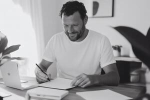 Creative brainstorming session unfolds as a man pens ideas in a serene, sunlit workspace adorned with greenery photo