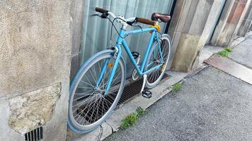 Bright blue bicycle resting against an urban wall photo