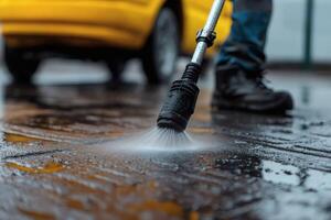 Power washing a wet driveway with attention to detail on a cloudy day beside a yellow car photo