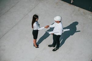 Successful, deal, doing handshake. Man with woman are working on the construction project together outside photo