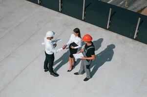 Doing ,,handshake. Top view of men and woman that are on construction site, working together on the project photo
