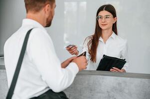 At reception. Man in ,white shirt is ordering a room in the hotel by woman's help photo
