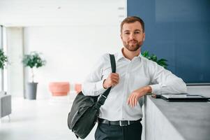 Standing at,, reception. Elegant man in formal clothes is indoors photo