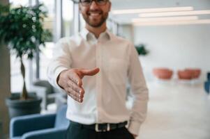 Giving, hand to make handshake. Elegant man in formal clothes is indoors photo