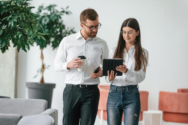 Using, digital tablet. Man and woman ,in formal clothes are working together indoors