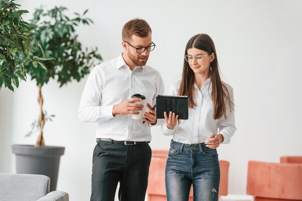 Using ,digital tablet.. Man and woman in formal clothes are working together indoors
