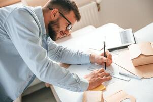 Doing measurements and drawing new design. Print house worker in white clothes is indoors photo
