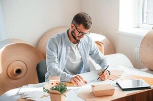 Drawing by the table.. Print house worker in white clothes is indoors photo