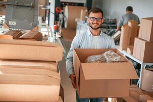Moving ,the boxes, with raw material. Print house worker in white clothes is indoors photo