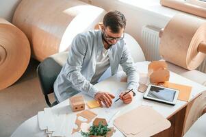 Sitting, and working by the table. Print house employee in white clothes is indoors photo
