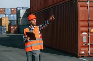 Giving, instructions, by the hand. Male worker is on the location with containers photo