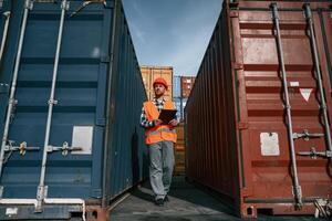 Male ,worker is on the location with containers. Using digital tablet photo