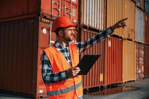 Digital tablet in hands.. Male worker is on the location with containers photo