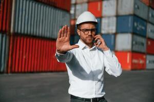 No way here. Talking by phone. Male worker is on the location with containers photo