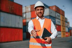 Giving hand to ,make handshake, successful deal. Male worker is on the location with containers photo