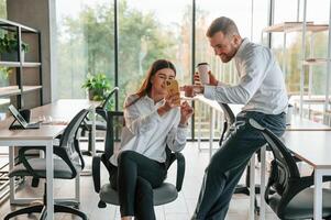 Having a break,, talking, using smartphone. Man and woman are working in the modern office together photo