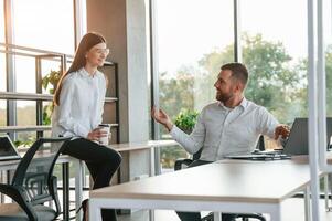 Having ,a conversation. Man and woman are working in the modern office together photo
