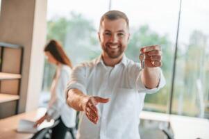 Holding keys for the new apartment. Man and woman are working in the modern office together photo