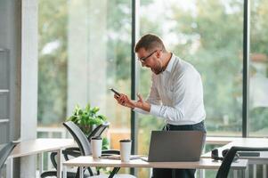 Screaming, feeling, angry. Man in formal clothes is working in the modern office photo