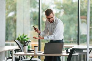 Screaming,, feeling angry. Man in formal clothes is working in the modern office photo