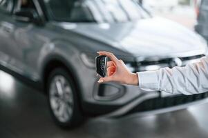 Close up view of keys... Young woman in white formal clothes is in the at dealership photo