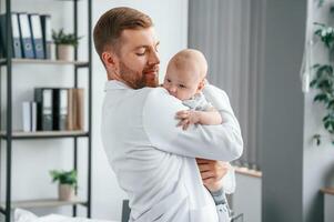 Doctor, in white coat is taking care of little toddler indoors photo