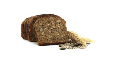Slices of whole grain bread are decorated with wheat stalks and assorted seeds on a white surface. photo