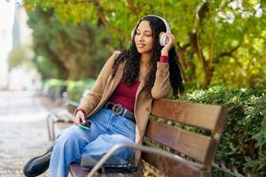A Young Woman Sitting on a Bench, Enjoying Music in a Peaceful Park Setting, Relaxing photo