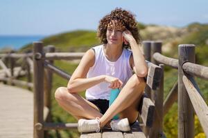 Smiling woman sitting on fence with water bottle photo