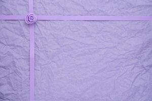 Crinkled violet paper with ribbon and rosebud texture photo