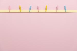 Pastel-colored clothespins attached to paper strips on a soft pink background, perfect for spring, Easter, or minimalist decor projects. Scrapbooking, DIY crafts, invitations, or festive decorations. photo