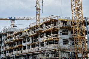 Modern building under construction with concrete structure and cranes photo
