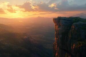Mountain landscape with large cliff over vast valley. Panoramic view of rocky edge at sunset photo